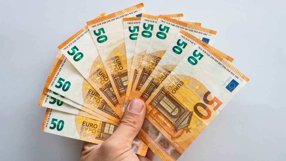 Mano sosteniendo abanico de billetes de 50 €, símbolo del microcrédito de 600 € del SEPE para formación laboral