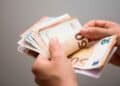 Manos contando billetes de 50 € que ilustran la ayuda del SEPE de 570 € mensuales por cotizaciones insuficientes