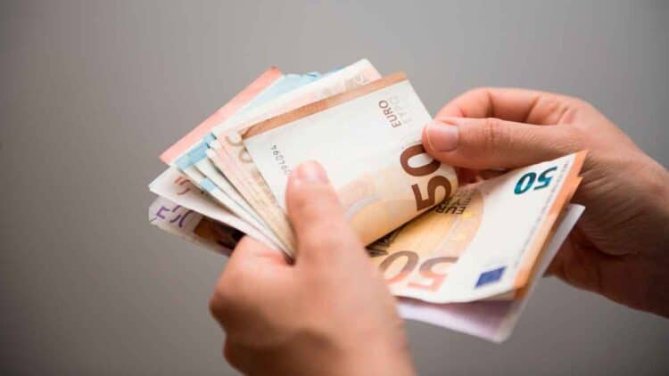 Manos contando billetes de 50 € que ilustran la ayuda del SEPE de 570 € mensuales por cotizaciones insuficientes