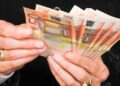 Manos de jubilada contando billetes de 50 €, símbolo de la pensión media de 1.505 € alcanzada en mayo