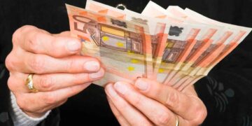 Manos de jubilada contando billetes de 50 €, símbolo de la pensión media de 1.505 € alcanzada en mayo