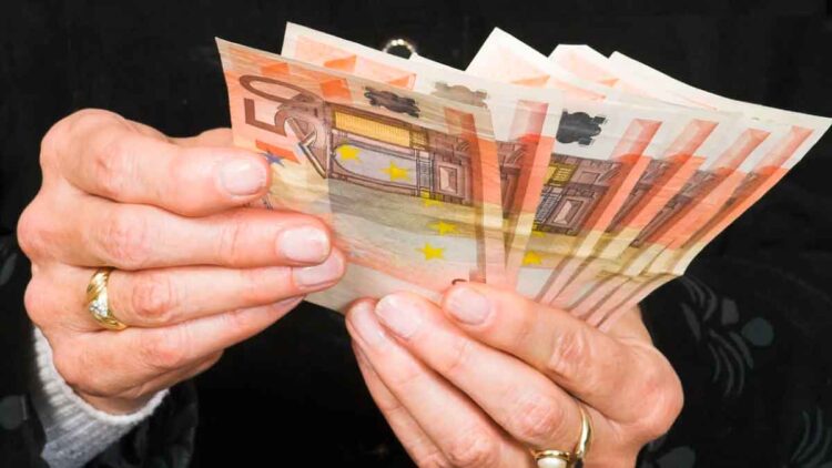 Manos de jubilada contando billetes de 50 €, símbolo de la pensión media de 1.505 € alcanzada en mayo