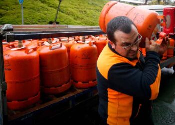 Repartidor cargando bombona de butano Repsol en una calle, tras la subida de precio en mayo de 2025