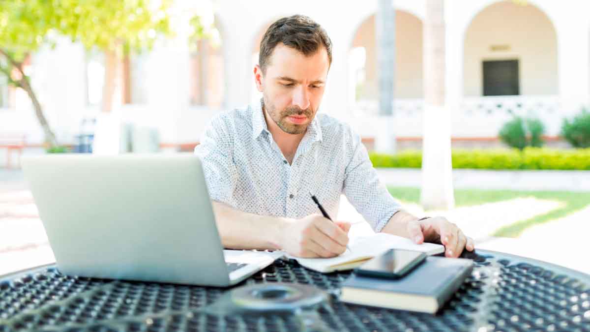 Autónomo trabajando al aire libre con portátil y cuaderno, beneficiándose de la tarifa plana de 80 € y un ahorro de 220 € mensuales