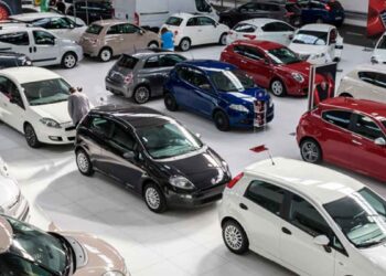 Vista de concesionario de coches de segunda mano con varios vehículos; alerta sobre estafas de cuentakilómetros, robos e inundaciones