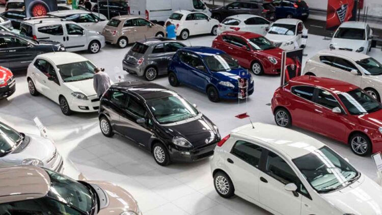 Vista de concesionario de coches de segunda mano con varios vehículos; alerta sobre estafas de cuentakilómetros, robos e inundaciones