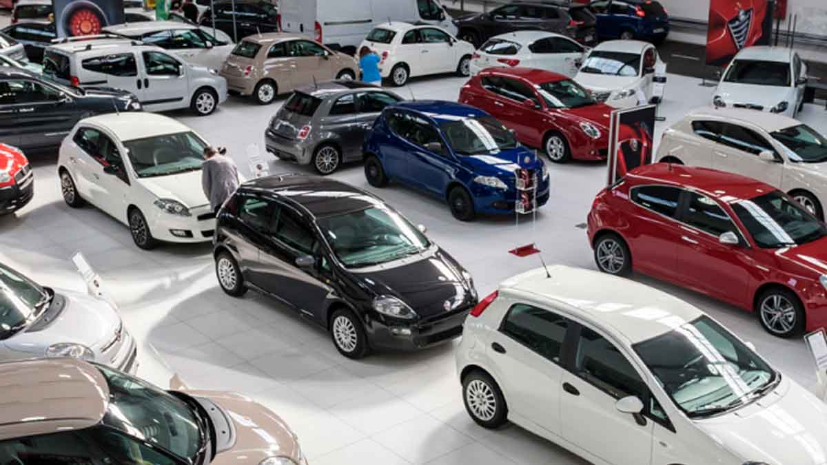 Vista de concesionario de coches de segunda mano con varios vehículos; alerta sobre estafas de cuentakilómetros, robos e inundaciones