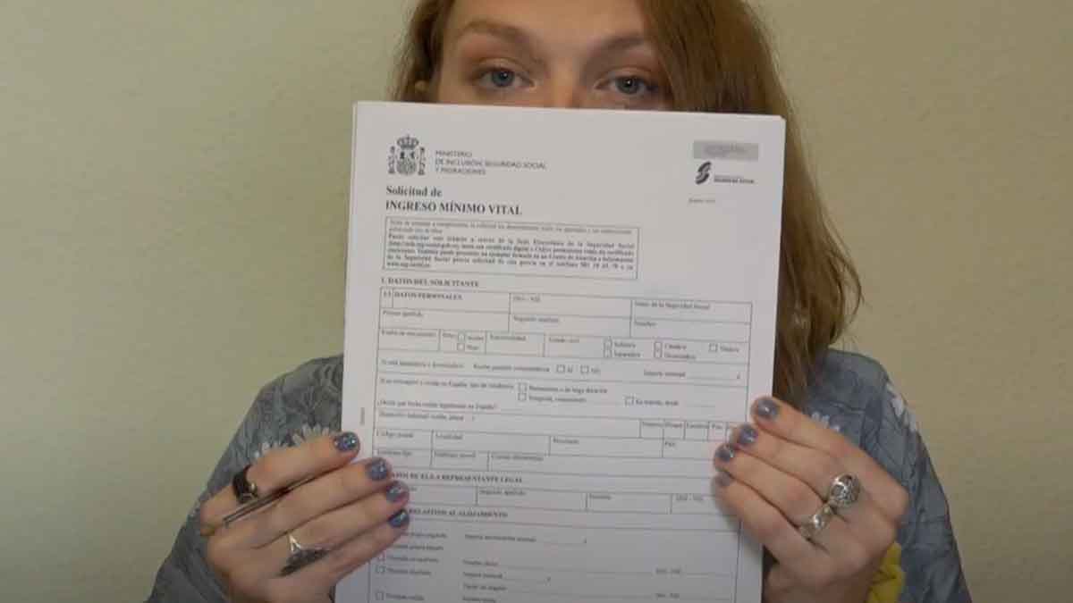Mujer muestra formulario solicitud Ingreso Mínimo Vital para comprobar estado aprobado, denegado o en trámite