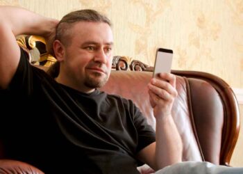 Hombre usando el móvil en casa mientras intenta controlar su tiempo en redes sociales