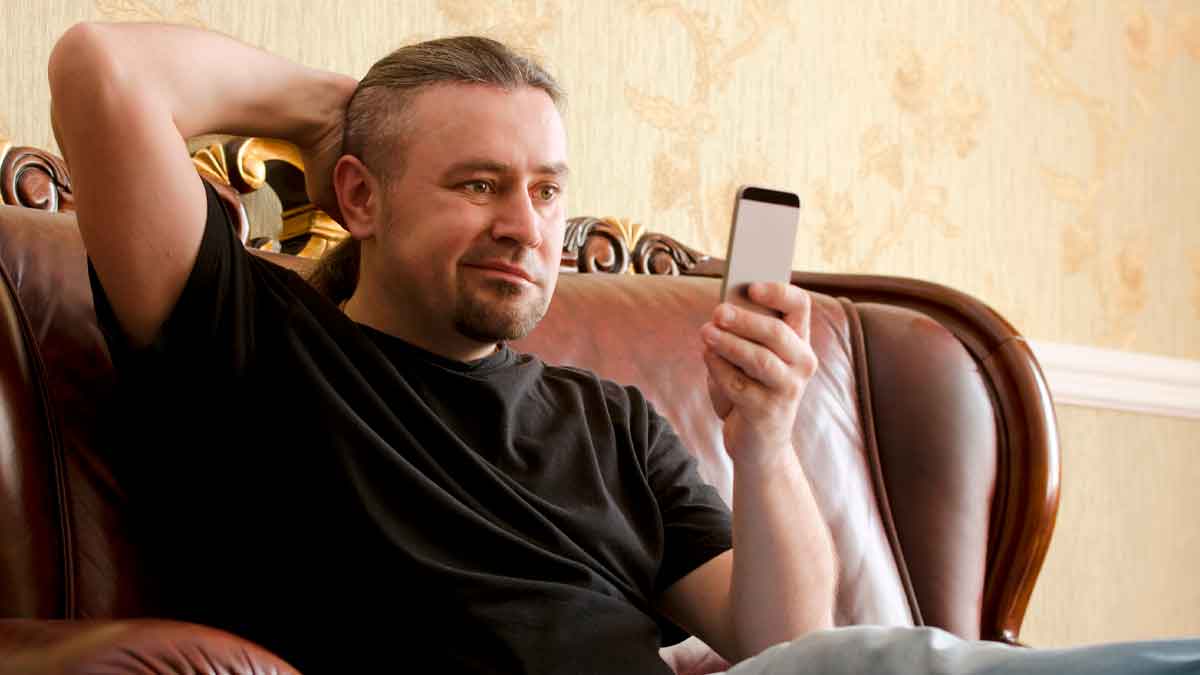 Hombre usando el móvil en casa mientras intenta controlar su tiempo en redes sociales