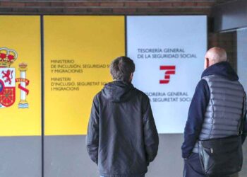 Dos personas frente a una oficina de la Seguridad Social en España para consultar sobre el complemento a mínimos en 2025