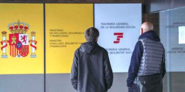 Dos personas frente a una oficina de la Seguridad Social en España para consultar sobre el complemento a mínimos en 2025