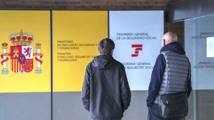 Dos personas frente a una oficina de la Seguridad Social en España para consultar sobre el complemento a mínimos en 2025