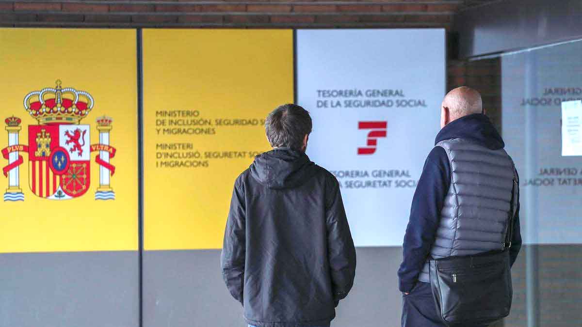 Dos personas frente a una oficina de la Seguridad Social en España para consultar sobre el complemento a mínimos en 2025