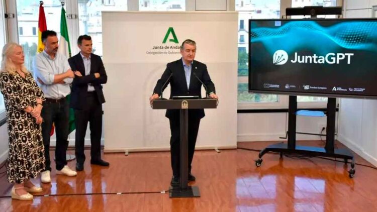 El consejero de la Junta de Andalucía, Antonio Sanz, presenta JuntaGPT junto a pantalla con el logo durante rueda de prensa