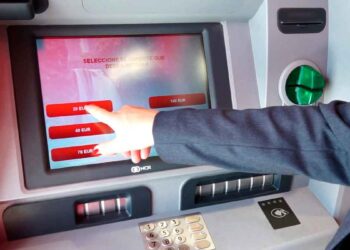 Cliente usando cajero automático seleccionando efectivo; riesgo de bloqueo de cuenta bancaria por incumplir la Ley 10/2010