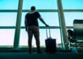 Hombre desempleado con maleta en un aeropuerto, a punto de viajar, arriesgando perder la prestación por desempleo del SEPE por no notificar la salida
