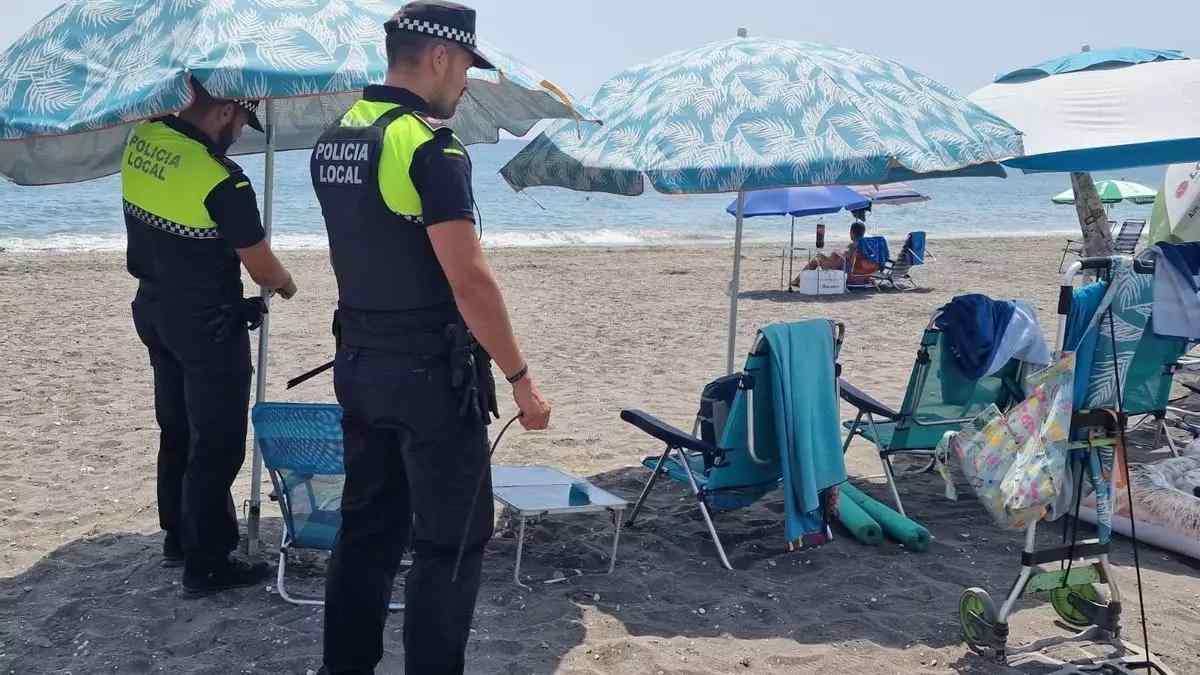 Policía Local retira sombrillas reservadas ilegalmente en una playa española.