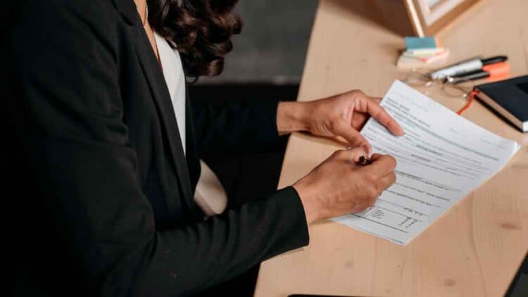 Mujer heredera firmando la declaración de la Renta de un familiar fallecido en una mesa de oficina