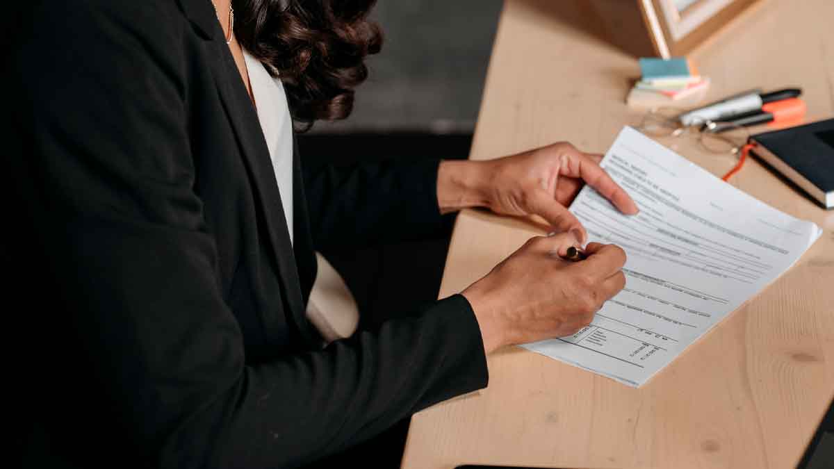 Mujer heredera firmando la declaración de la Renta de un familiar fallecido en una mesa de oficina