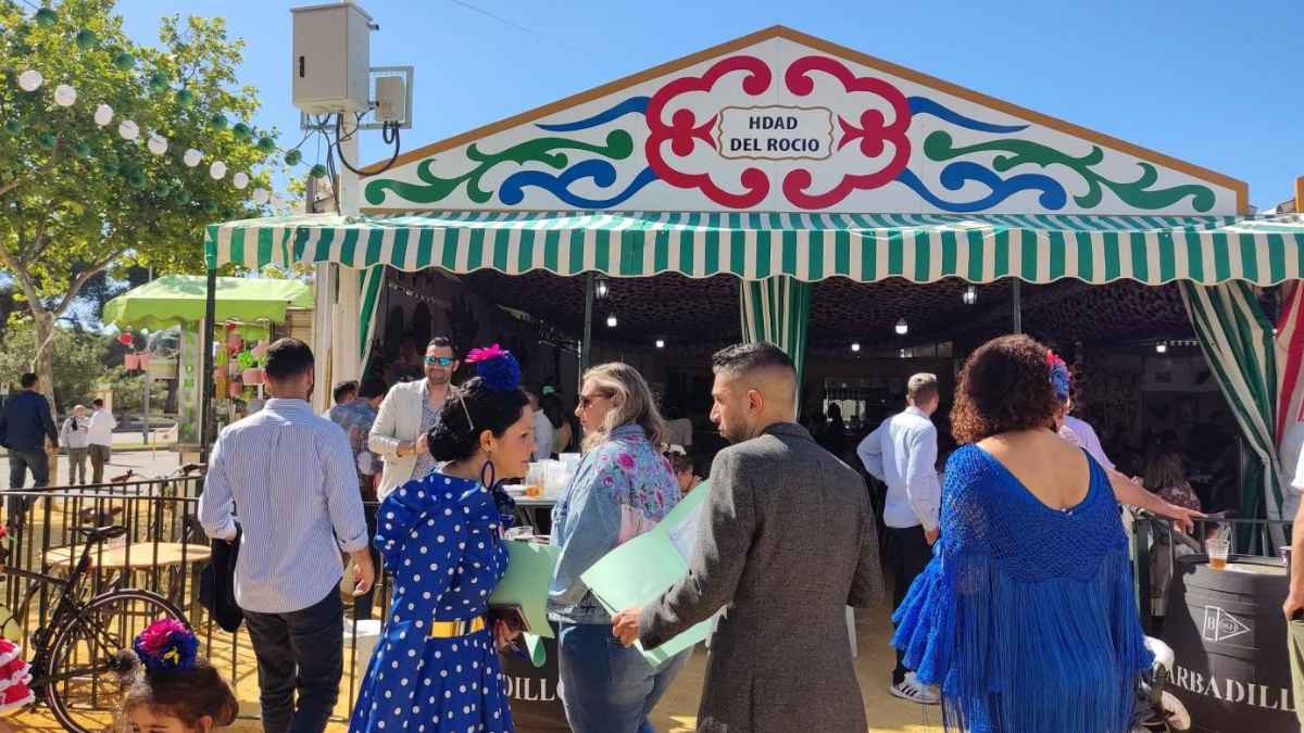 Caseta de la Hermandad del Rocío en la Feria de Córdoba 2025 con visitantes vestidos de flamenca.