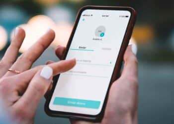 Mano de autónoma usando la app Bizum en el móvil para enviar dinero, operaciones que controlará Hacienda desde enero de 2026