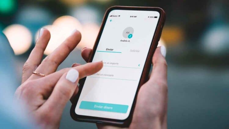 Mano de autónoma usando la app Bizum en el móvil para enviar dinero, operaciones que controlará Hacienda desde enero de 2026