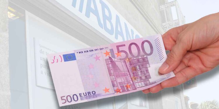 Mano sosteniendo un billete de 500 € frente a una sucursal bancaria, símbolo de las promociones de hasta 500 € por domiciliar la nómina en junio 2025