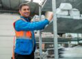 Empleado con chaleco reflectante organiza estanterías en un almacén; ejemplo de inclusión laboral de personas con autismo.