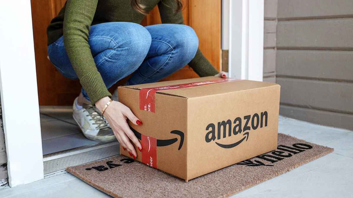 Mujer recogiendo paquete Amazon en la puerta, muestra de hogar habitado gracias a persianas automatizadas en vacaciones.