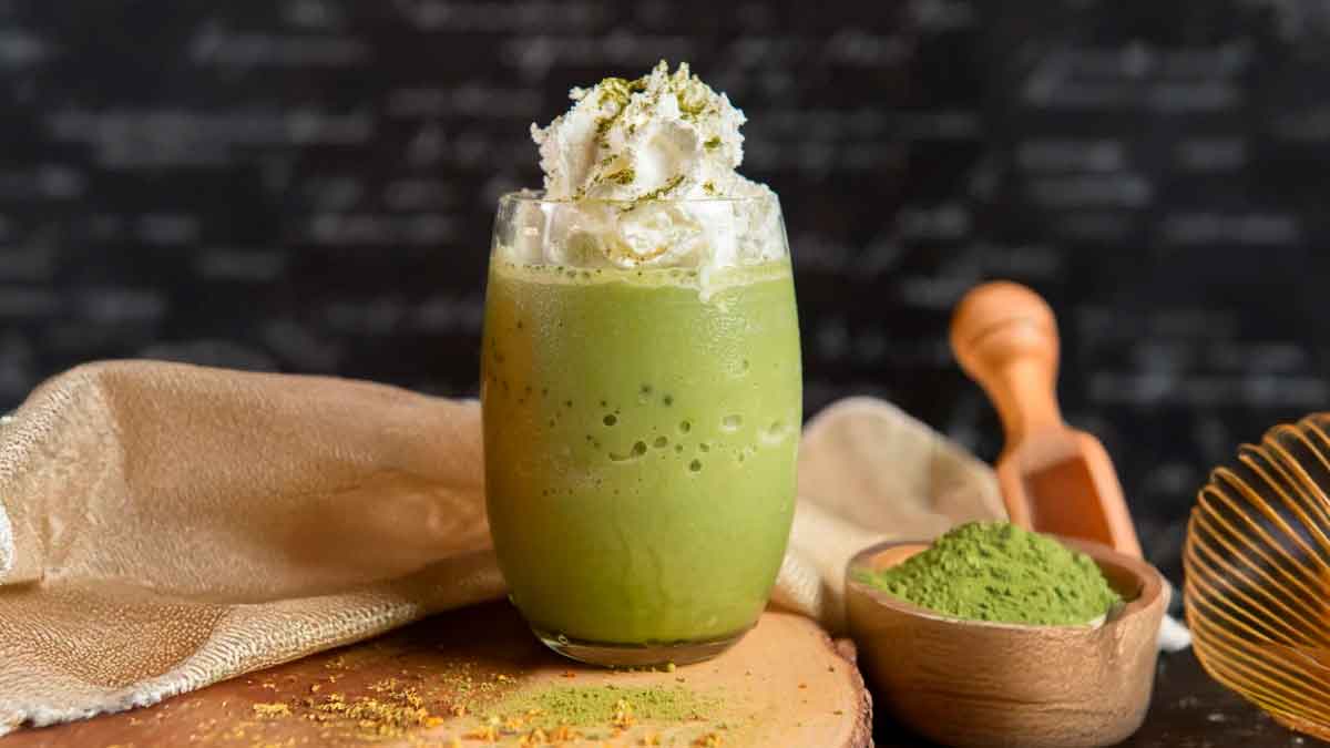 Bebida matcha latte con crema y polvo de té matcha sobre mesa de madera