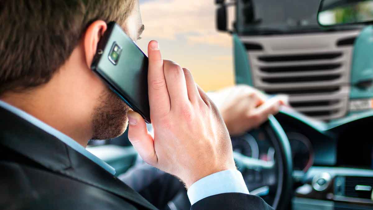 Hombre conduciendo mientras habla por teléfono móvil, motivo frecuente de multa por parte de la DGT