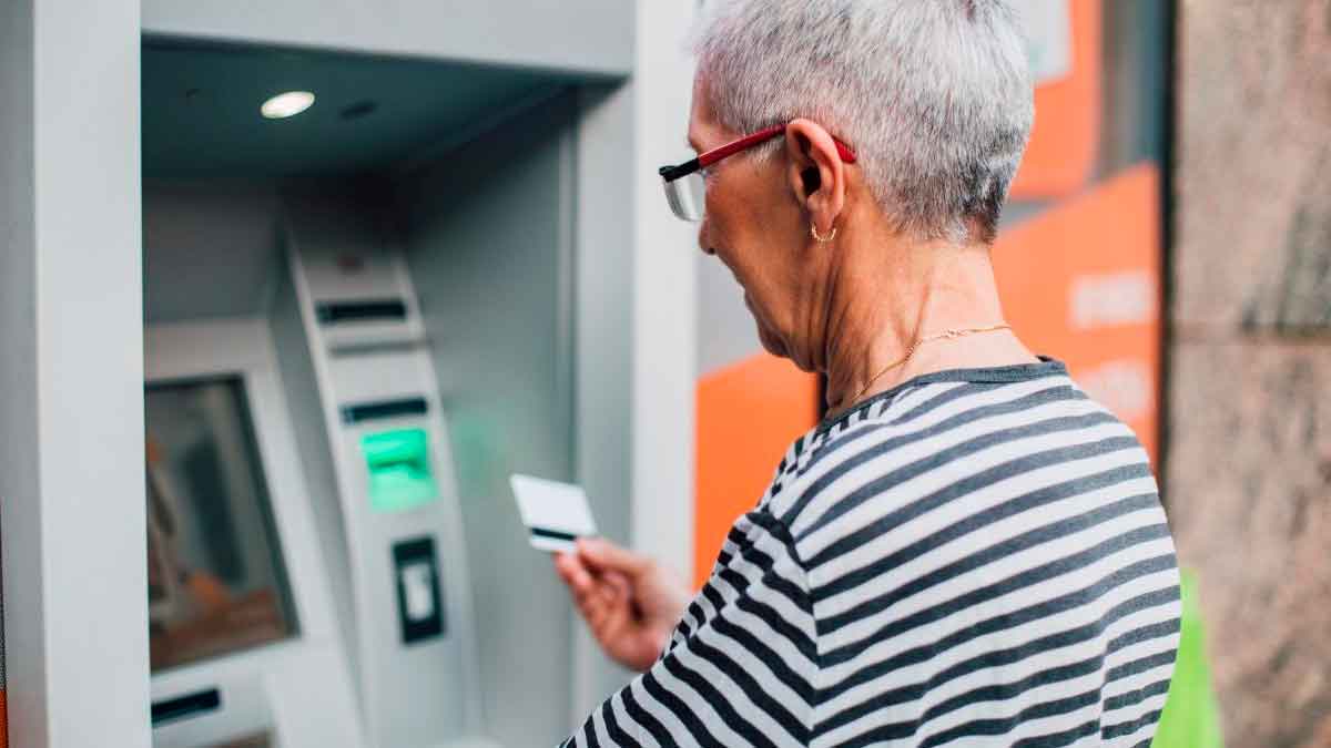 Persona mayor retirando pensión y paga extra de junio 2025 en cajero automático