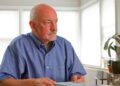 Hombre de 64 años revisa documentos tras un despido, valorando si cobrar el paro o jubilarse anticipadamente