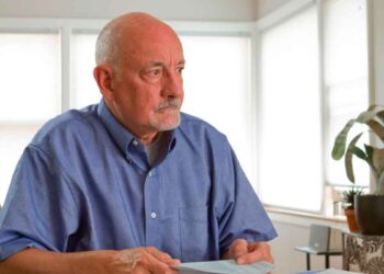 Hombre de 64 años revisa documentos tras un despido, valorando si cobrar el paro o jubilarse anticipadamente