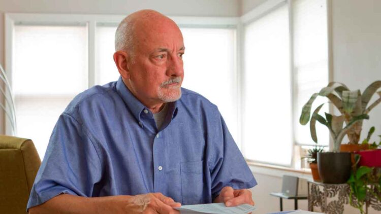 Hombre de 64 años revisa documentos tras un despido, valorando si cobrar el paro o jubilarse anticipadamente
