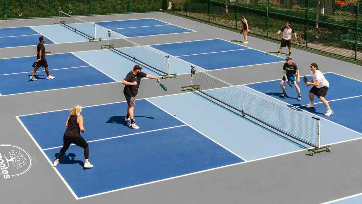 Jugadores de pickleball en Málaga compiten en dobles sobre pistas azules en el Pickle Pro Tour 2025 con 300 participantes.