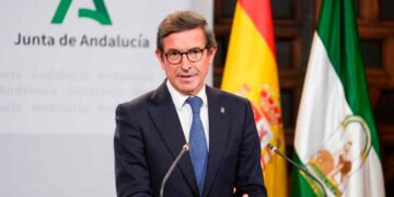 Jorge Paradela, consejero de Industria, presenta en rueda de prensa las ayudas del Plan MOVES III 2025, con banderas de España y Andalucía al fondo