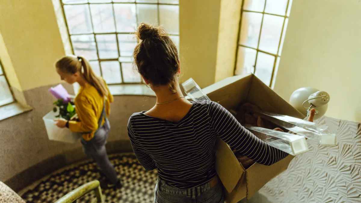 dos inquilinas se mudan con cajas por la escalera tras aviso del casero que necesita recuperar la vivienda.