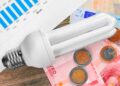 Bombilla de bajo consumo sobre euros y gráfico mensual, símbolo de ahorrar 10 % en la factura de la luz en verano