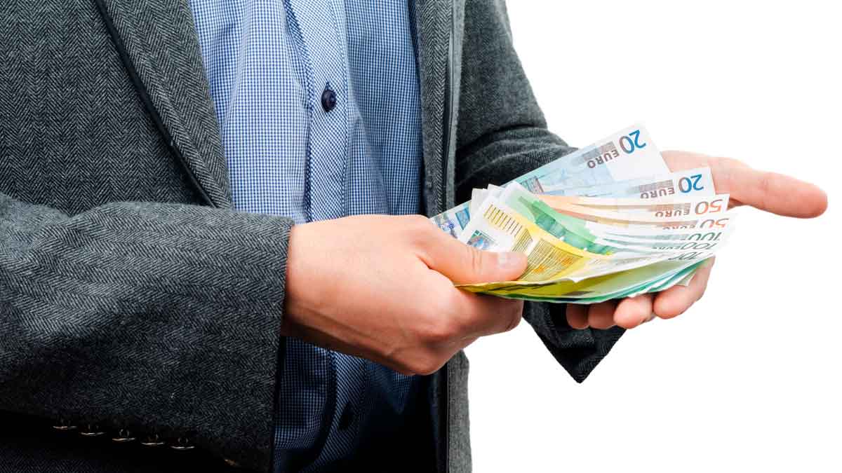 Trabajador con traje contando billetes de 20 € y 50 €, símbolo de la ayuda del SEPE de hasta 10.980 € para quienes han cotizado menos de 360 días.