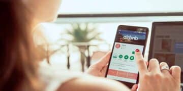 Mujer consultando la app de Airbnb en su móvil: alerta sobre el timo del cupón fantasma que reaparece cada verano