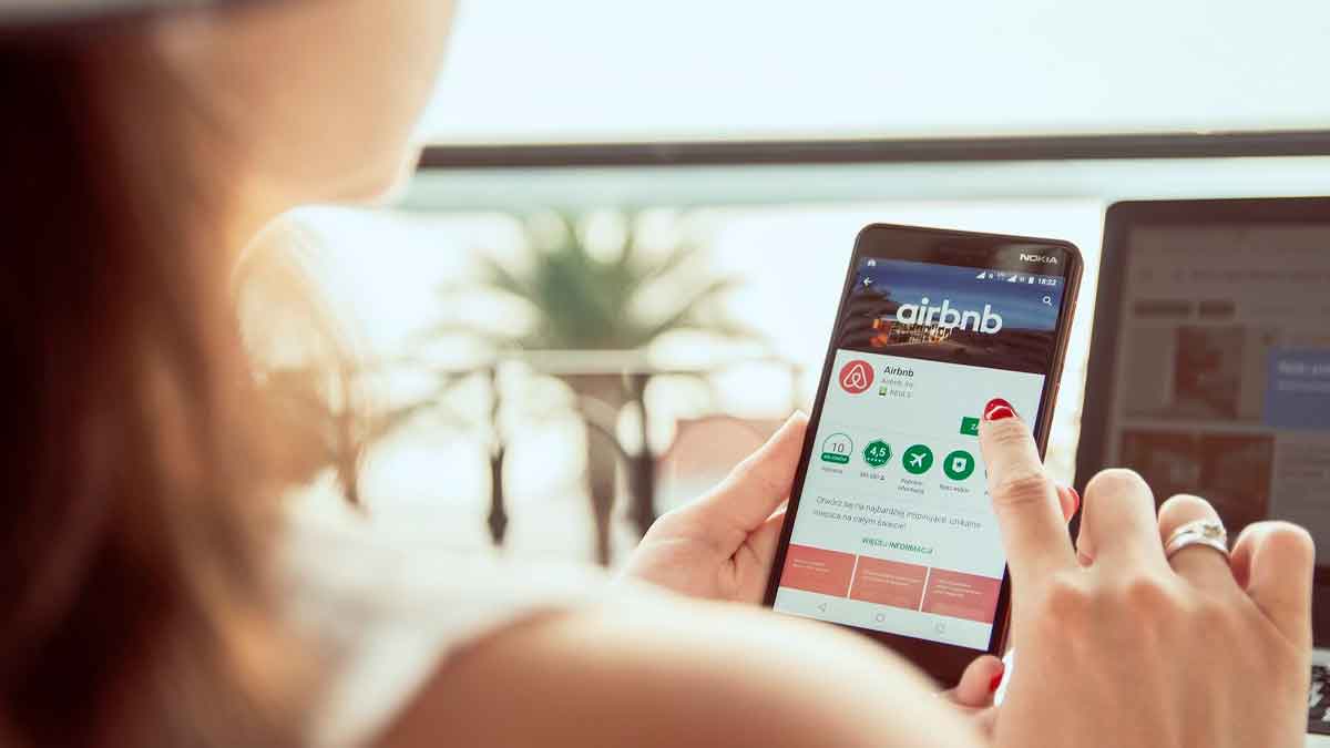 Mujer consultando la app de Airbnb en su móvil: alerta sobre el timo del cupón fantasma que reaparece cada verano