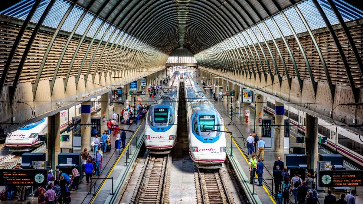 Trenes AVE de Renfe en estación con pasajeros, ilustrando los abonos gratuitos y descuentos 2025 para viajar más barato