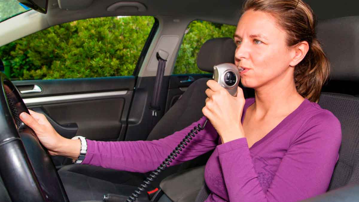 Mujer soplando en alcoholímetro Interlock instalado en coche para evitar conducción bajo efectos del alcohol