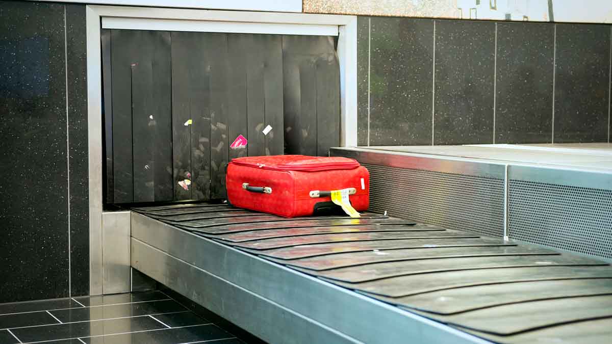 Maleta roja en la cinta transportadora del aeropuerto, ejemplo de cómo evitar perder el equipaje en vuelos con escala