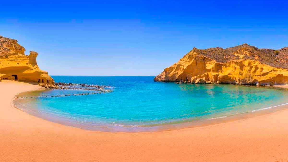 Cala de Los Cocedores en Almería con aguas cristalinas, arena fina y montaña en forma de casa al atardecer