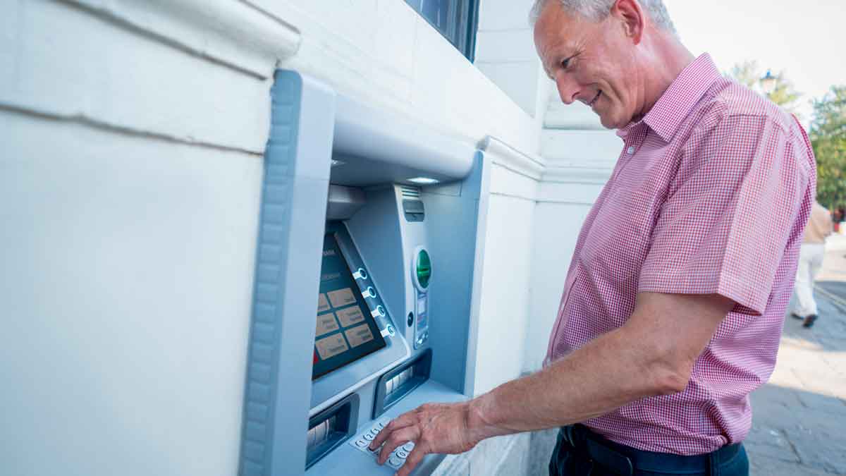 Pensionista consultando el calendario de pago de las pensiones de julio de 2025 en un cajero automático