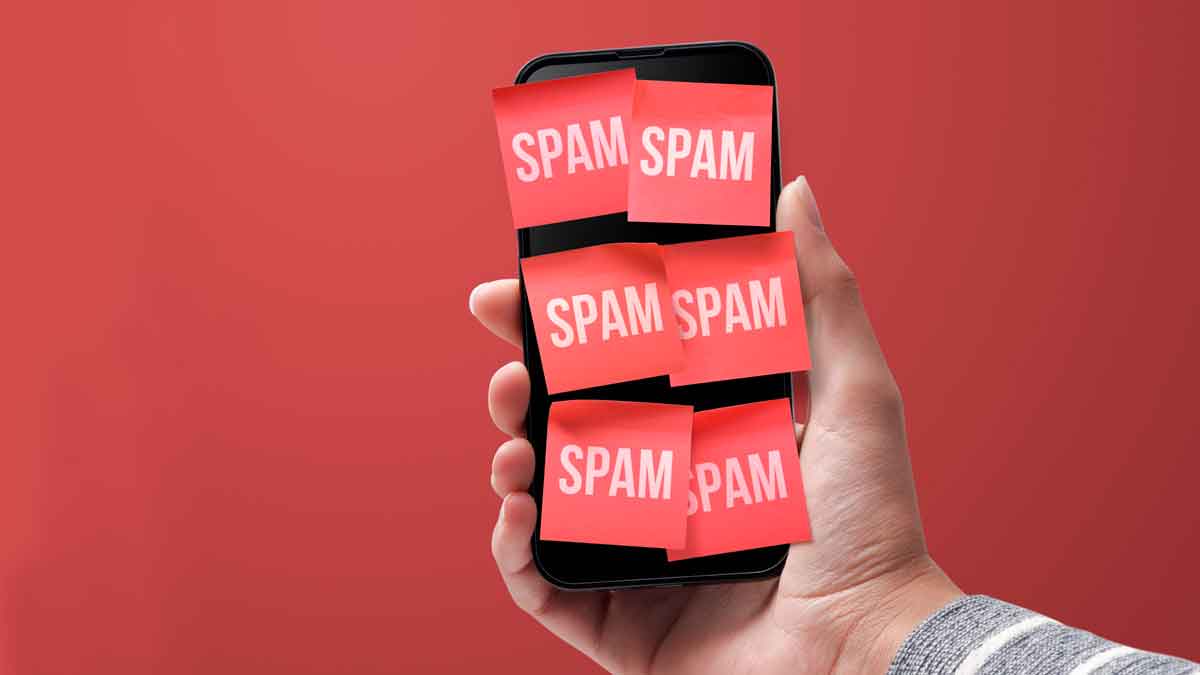 Teléfono móvil cubierto de notas rojas con la palabra spam que simboliza la opción de bloquear llamadas y mensajes en Android e iOS