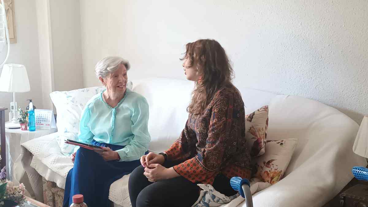 Joven conversando con ascendiente mayor en casa; convivencia con mayores de 65 años permite deducción IRPF hasta 2.550 euros.